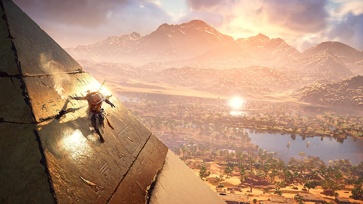 Video game cover showing a character climbing an ancient pyramid with hieroglyphics overlooking a vast desert landscape at sunset for Assassin's Creed Origins PS4.