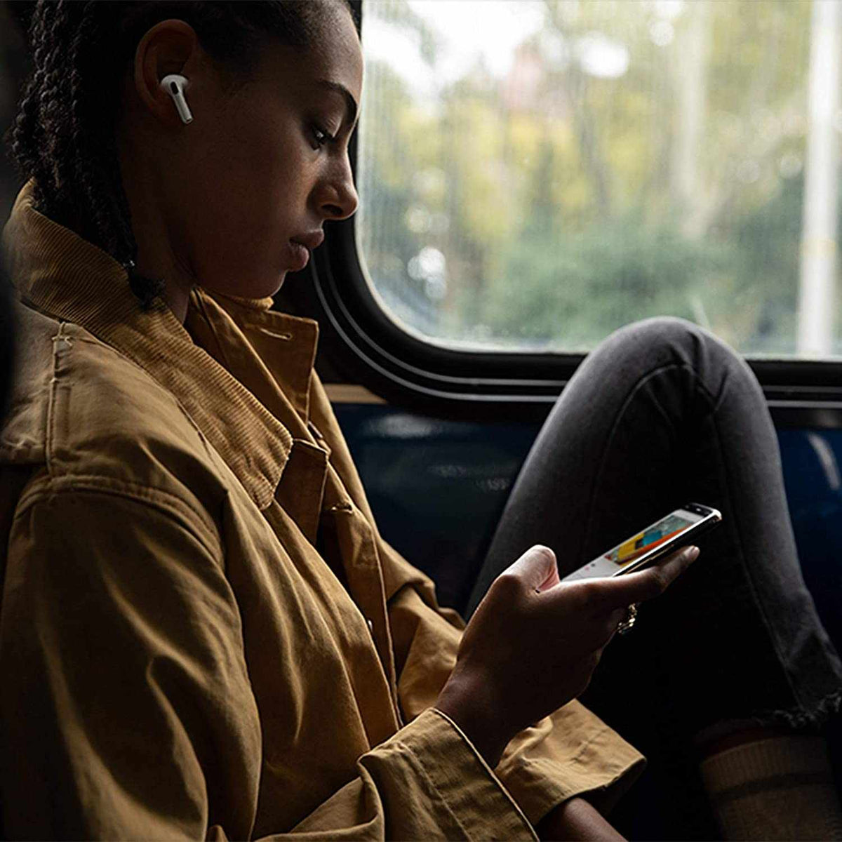 Wireless white Apple AirPods Pro earbuds worn by a person using a smartphone, featuring a sleek stem design and in-ear fit.