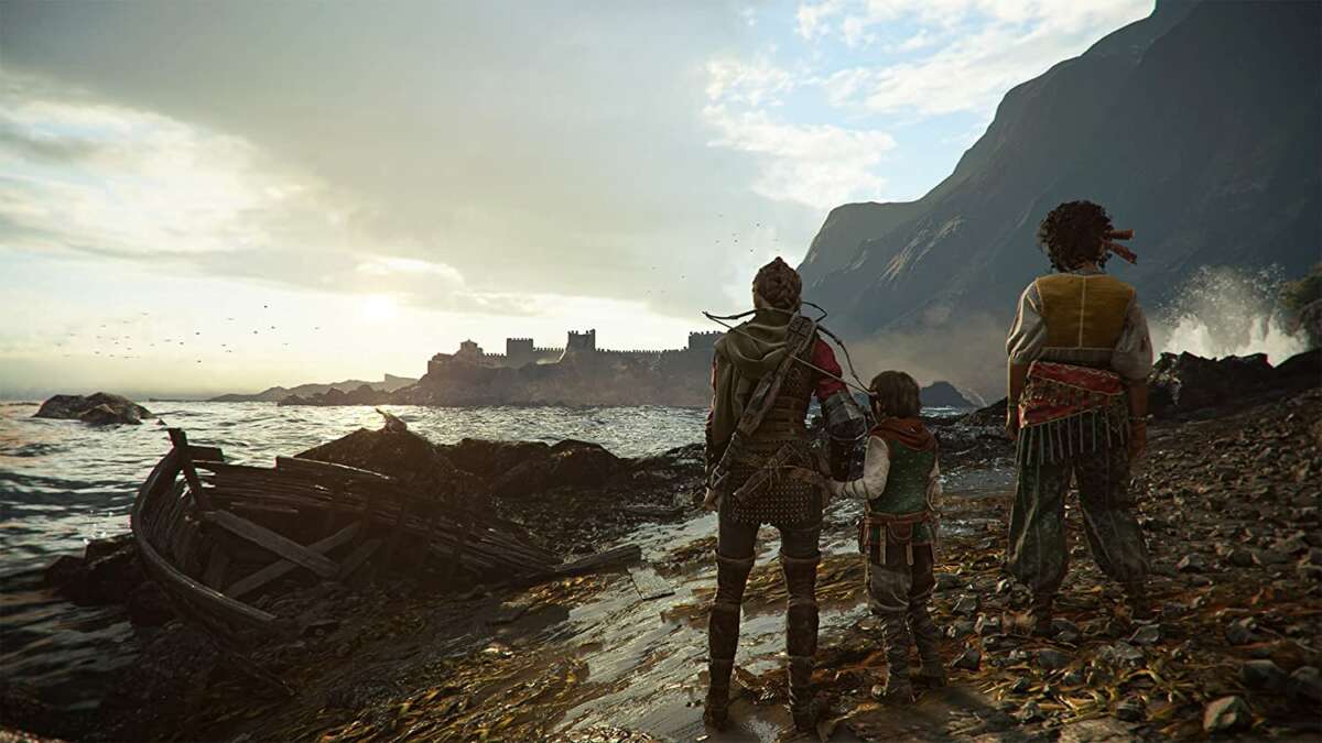 A Plague Tale: Requiem PS5 showing three characters in medieval attire overlooking a rocky shoreline with a ruined boat and distant castle.